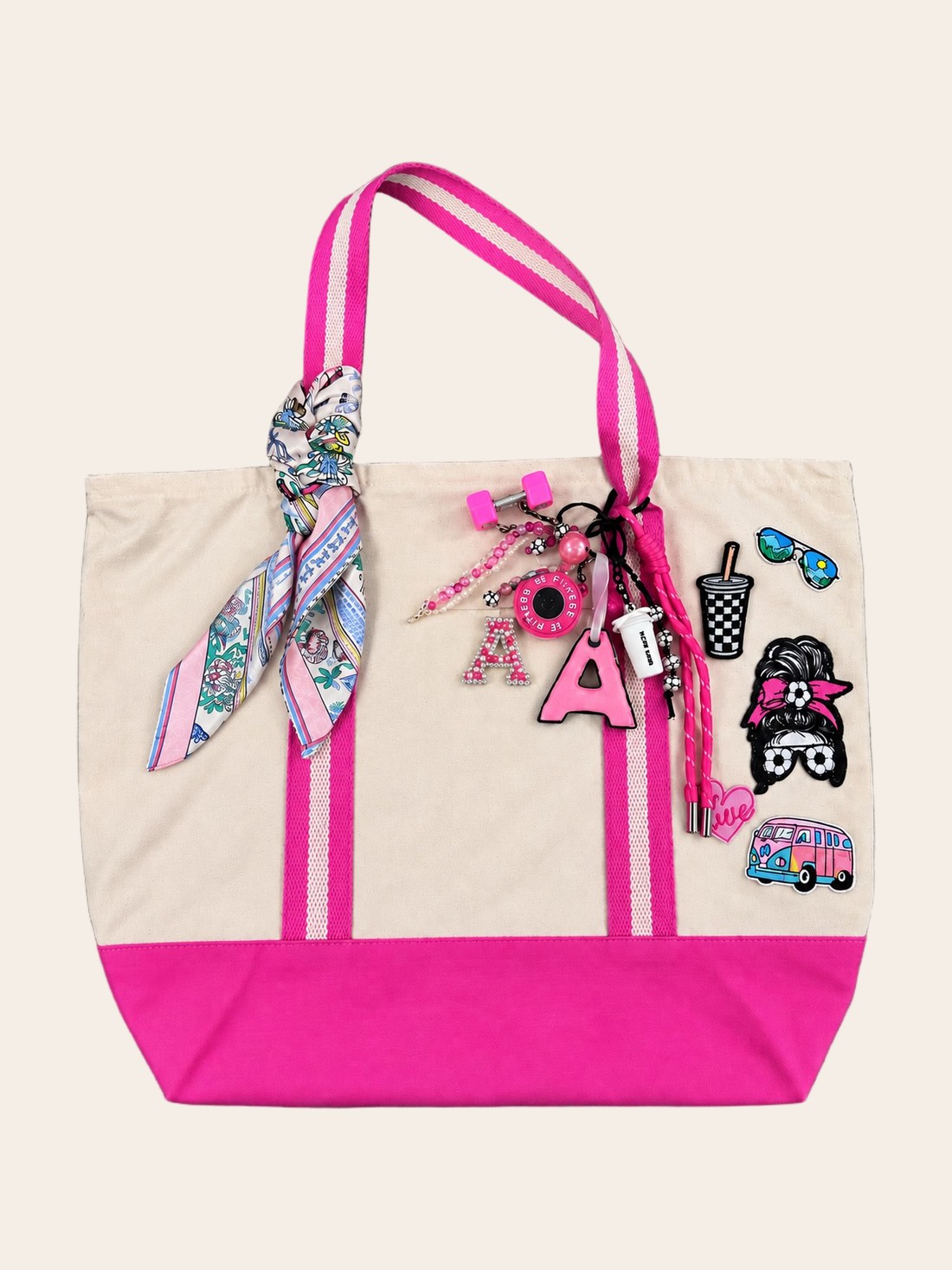 A cream and hot-pink canvas tote with an initial A patch, charms, sunglasses and a silk twilly.
